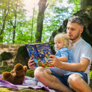 father and child with book teddy bear reading in nature